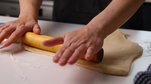 Rolling dough on a home kitchen counter with a wooden rolling pin