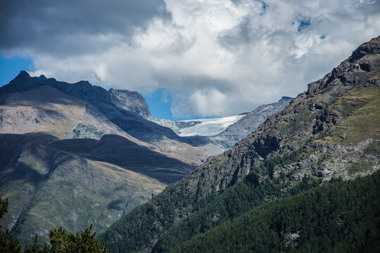 Clouds making shadows on the rocky Alps with snow of Parc National de la Vanoise
