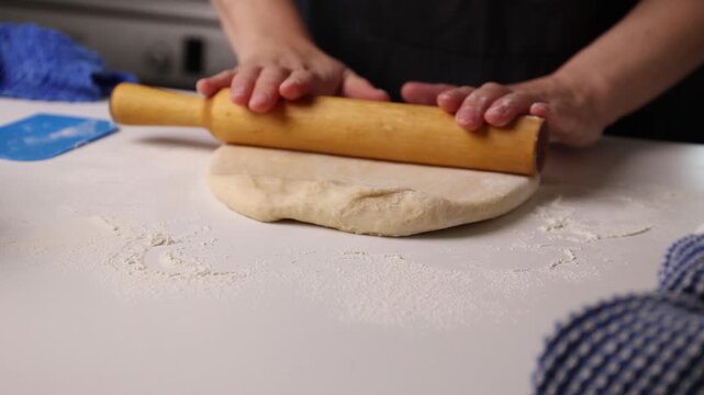 Dough being kneaded and rolled into a round disk on a flour-dusted counter