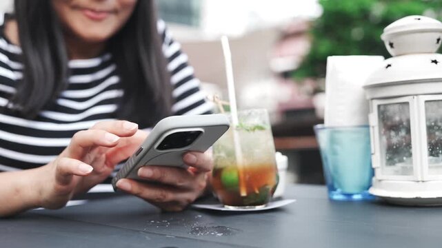 Woman using smartphone at outdoor cafe, middle aged female relaxing with iced drink and popcorn, casual lifestyle and mobile communication during leisure time, weekend break or after work