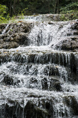 Multi-step limestone waterfall cascade with splashing water droplets in tropical jungle, Erawan National Park, Thailand © VaZu Photo