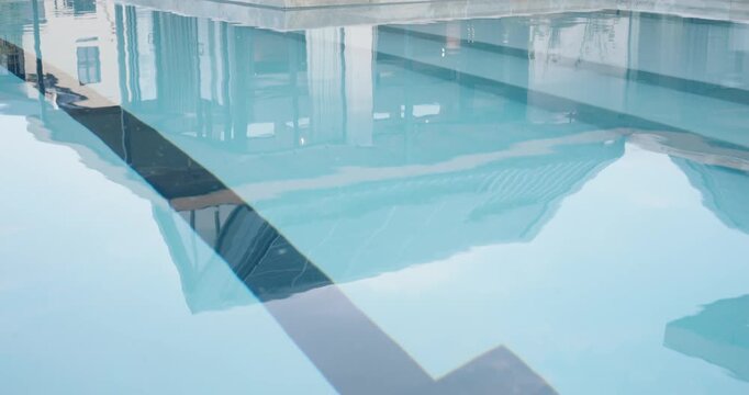 Camera is pulling back and tilting, revealing pool with T marker, steps, patio and solar panels
