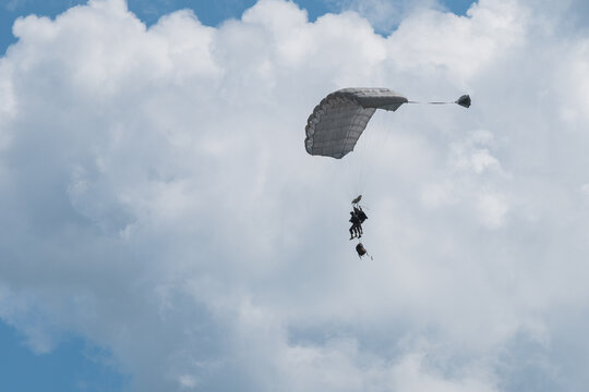 French paratrooper coming down under his canopy with his kit bag hanging below him above Caylus, France