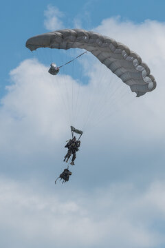 Full combat load hanging under the canopy of a descending French military paratrooper above Caylus, France