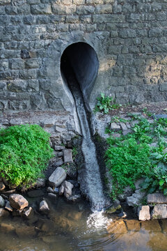 Water discharging from arched stone culvert into stream