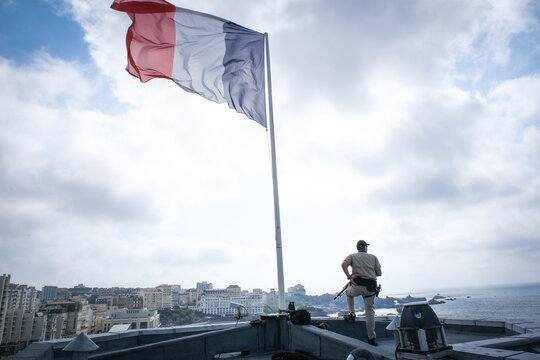 Silhouette of a French police operator under the French flag on a roof during summit security in Biarritz, France