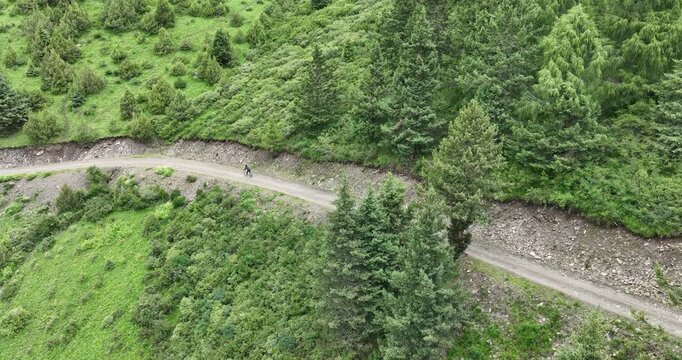 Aerial footage of woman riding mountain bike on beautiful forest mountain trail