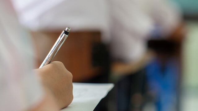Close-up of Student Hand Writing on Exam Paper with Pen
High School Student Taking Standardized Test with Concentration on Wooden Desk