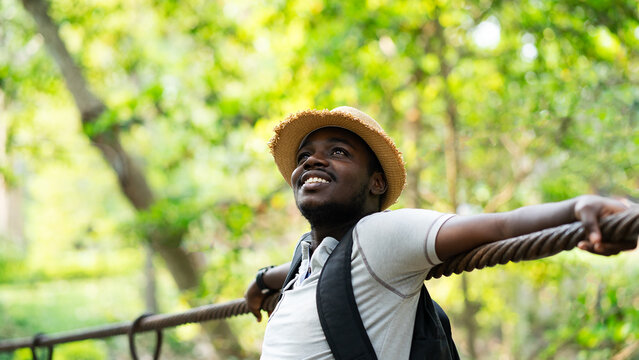 Happy African Male Tourist Standing on Suspension Bridge Enjoying Nature View