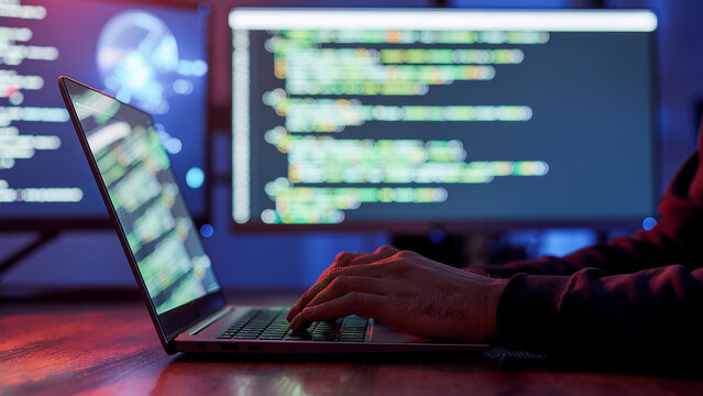 Software developer writing code on a laptop in a dark office
