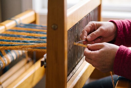 Hands weaving colorful yarn on traditional loom
