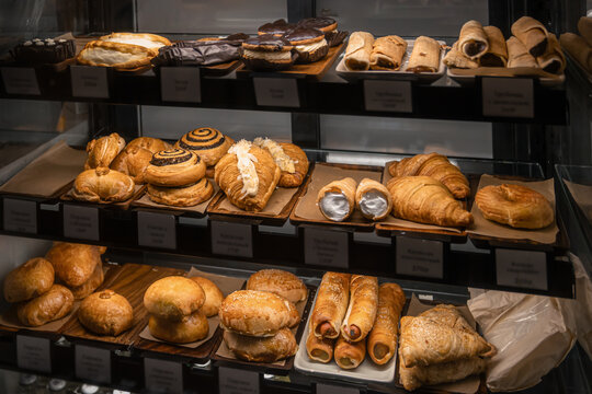 Assortment of fresh croissants, pastries, sweet buns and baked goods displayed in a glass bakery showcase