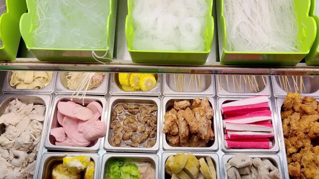 Assorted Wok Ingredients on Display in Asian Restaurant &ndash; Fresh Mushrooms, Greens, Sliced Vegetables, Various Noodles, Glass Noodles, Meatballs, Shrimp and Chicken for Custom Stir-Fry