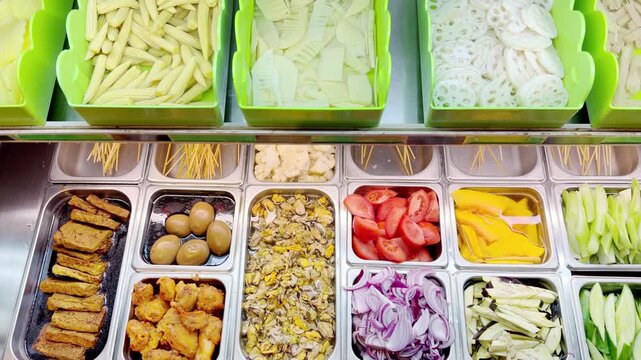 Assorted Wok Ingredients on Display in Asian Restaurant &ndash; Fresh Mushrooms, Greens, Sliced Vegetables, Various Noodles, Glass Noodles, Meatballs, Shrimp and Chicken for Custom Stir-Fry