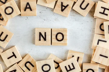 Small wooden tiles with letters scattered on white table, two in middle spell word NO © Lubo Ivanko
