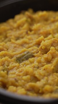 Freshly Cooked Yellow Moong Dal Khichdi with Turmeric Served Hot in a Black Bowl, Close-Up Food Shot.