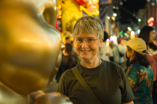 Tourist smiles next to Billiken Statue in Shinsekai Market, Osaka