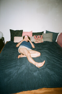 Relaxing at home reading a book on a dark green bed