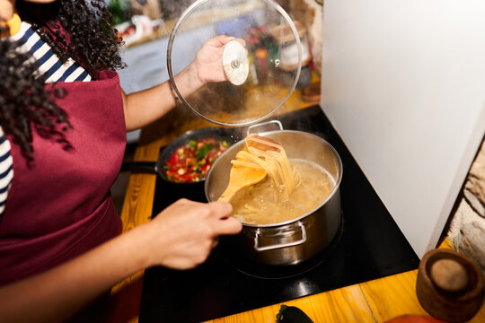 Woman cooking pasta on stove for dinner meal
