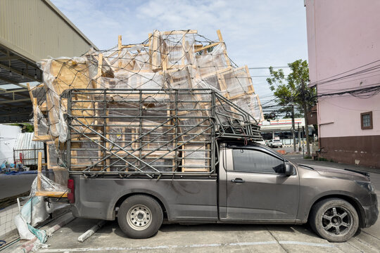 Pickup truck carrying a load of plastic-wrapped furniture in Bangkok