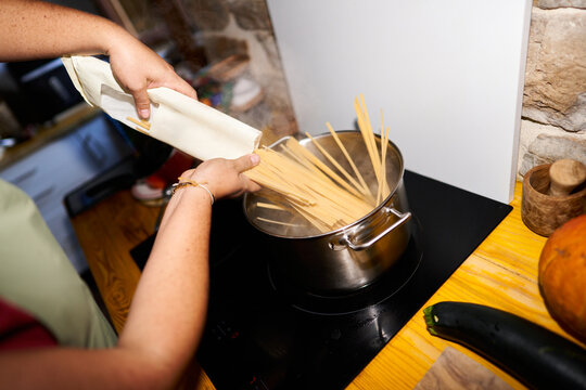 Person cooking spaghetti pasta in boiling water pot