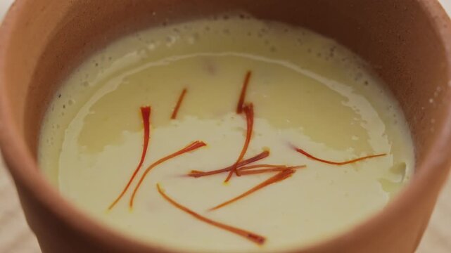Creamy Traditional Indian Lassi Topped with Saffron Strands Served in a Rustic Clay Cup, Close-Up Beverage Shot