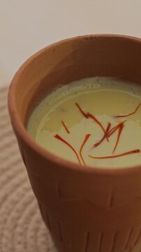 Creamy Traditional Indian Lassi Topped with Saffron Strands Served in a Rustic Clay Cup, Close-Up Beverage Shot