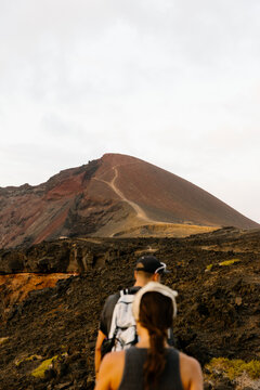 Athletic friends hiking on a Lanzarote volcano with panoramic views.