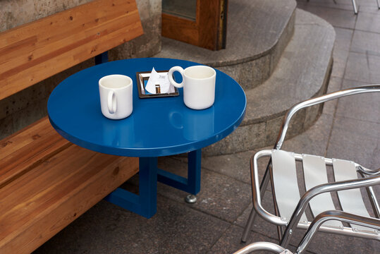Two white cups on blue table at cafe