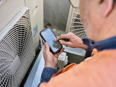 Aircon service person using software on mobile device.