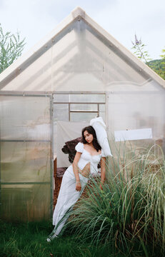 Chinese woman leaning against a pillow in a garden sunroom