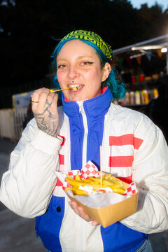 Smiling woman enjoying french fries in a fair