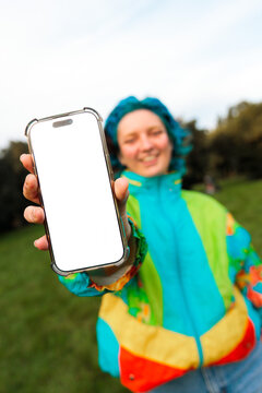 Woman showing blank phone screen outdoors