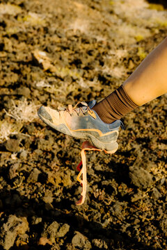 Shoe with a detached sole on a volcanic rock outcrop at sunset.