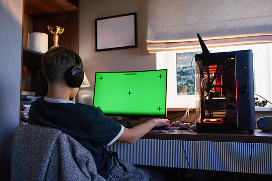 Teen boy playing video games on gaming PC at desk