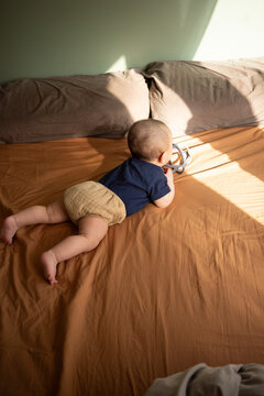 Infant Playing on Sunlit Bed