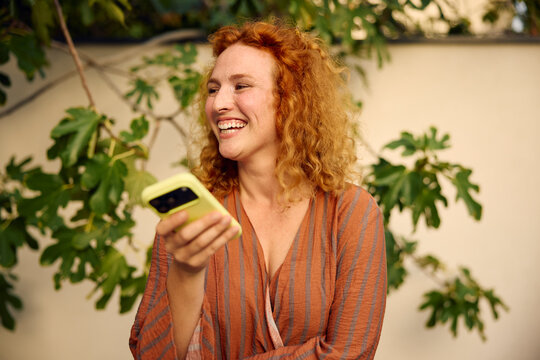 Happy woman uses her phone outdoors