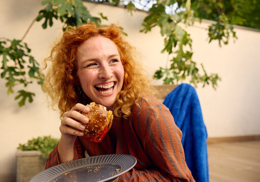 Woman eats a burger and smiling