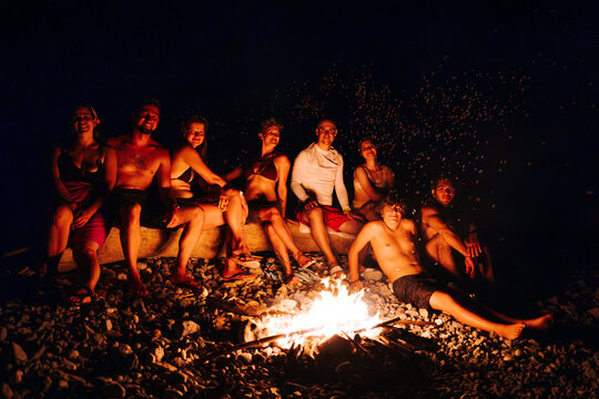 friends around a campfire with sparks rising at night