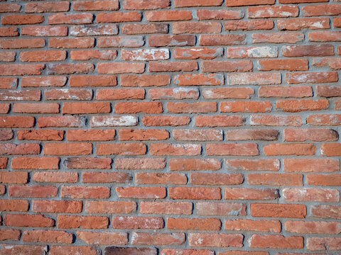 Full frame texture of a rustic red brick wall with gray mortar joints and weathered clay bricks.Architectural background for construction,renovation,interior design and building materials advertising.