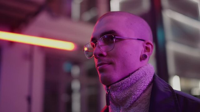 A young, fashionable man in the neon lights at night