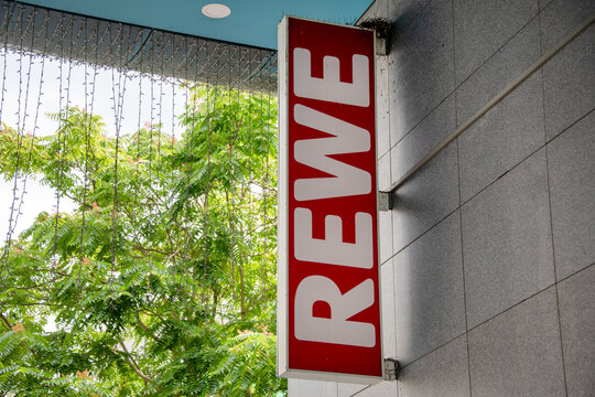 Berlin, Germany - 16 August 2026. REWE supermarket storefront with red signage on an urban building in Germany. Grocery retail, brand, shopping, consumerism, convenience, commerce.