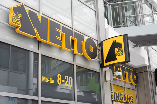 Berlin, Germany - 16 August 2026. Netto supermarket storefront with bold yellow sign and opening hours on a modern shopping center. Retail, shopping, commerce, urban architecture, consumer culture.