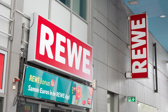 Berlin, Germany - 16 August 2026. REWE supermarket storefront with red signage on an urban building in Germany. Grocery retail, brand, shopping, consumerism, convenience, commerce.