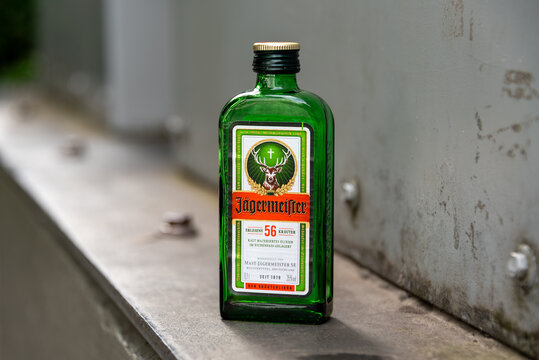 Berlin, Germany - 16 August 2026. A green J&auml;germeister bottle sits on a concrete ledge outdoors. Close-up liquor product photo, herbal liqueur, alcohol, party and nightlife themes.