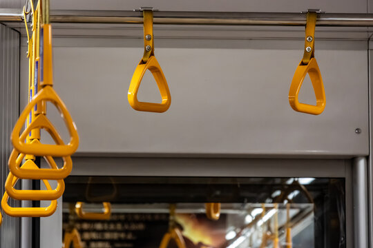 Yellow passenger hand straps hanging inside modern commuter train interior in Tokyo Japan