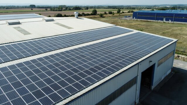 Large solar array on industrial warehouse roof providing sustainable energy solution.