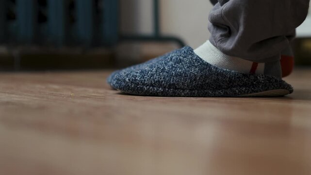 Close up of person feet wearing warm slippers on floor at home