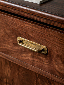 Close up of aged brass hardware on a walnut cabinet