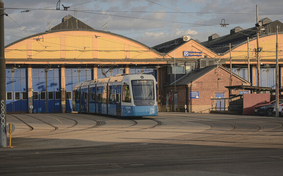 Gothenburg, Sweden - August 26 2026: Blue Gothenburg tram leaving traditional yellow urban depot building.